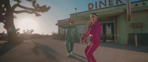 A Couple Dancing In Front Of A Diner That Has The Word Diner On It GIF