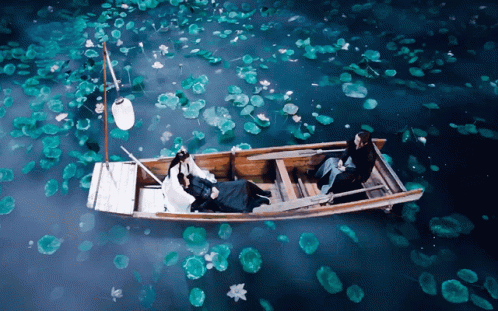 A Couple In A Boat With A Lantern Floating In The Water GIF