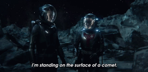 a couple of astronauts are standing on the surface of a comet