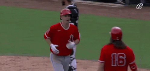 A Couple Of Baseball Players Are Hugging Each Other On A Field . GIF