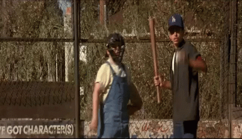 A Couple Of Boys Are Standing Next To Each Other In Front Of A Fence . GIF