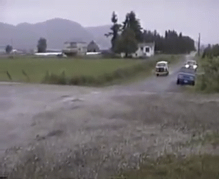 A Couple Of Cars Are Driving Down A Road In The Rain GIF