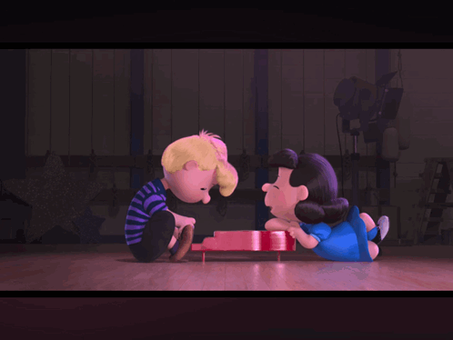 A Couple Of Cartoon Characters Sitting Next To Each Other On A Stage GIF