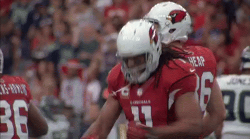 A Couple Of Football Players Are Hugging Each Other On The Field . GIF