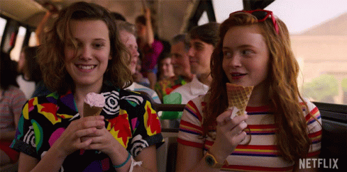 A Couple Of Girls Are Eating Ice Cream Cones On A Bus . GIF