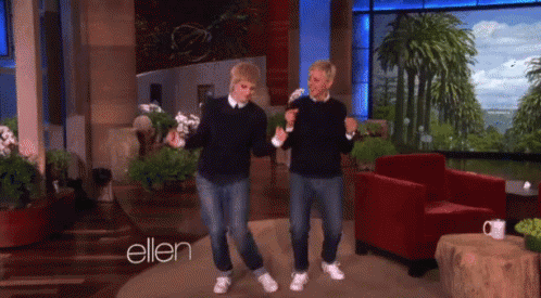 A Couple Of Men Are Dancing In Front Of A Sign That Says Ellen GIF