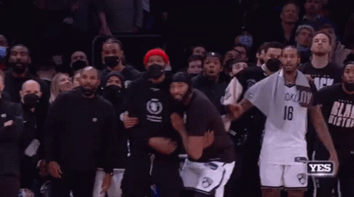 A Couple Of Men Are Hugging Each Other In Front Of A Crowd . GIF