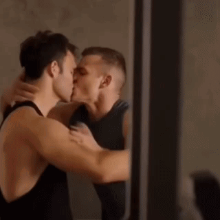 a couple of men are kissing each other in front of a mirror .