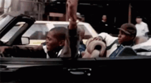 A Couple Of Men Are Sitting In A Convertible Car Holding Hands . GIF