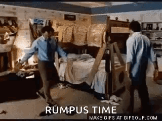 A Couple Of Men Are Standing Next To A Bunk Bed In A Messy Room . GIF