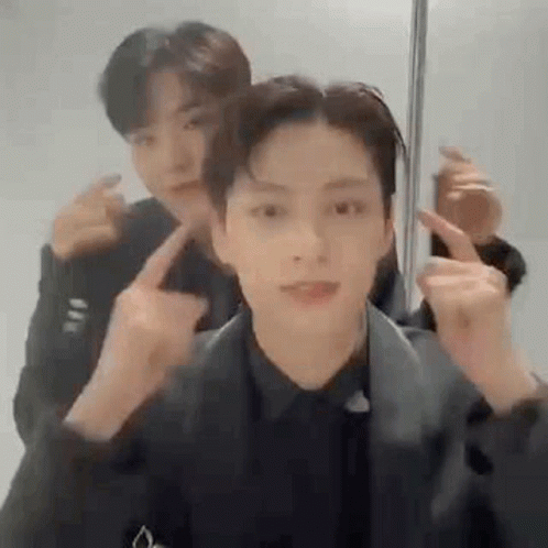 A Couple Of Men Are Standing Next To Each Other And Making Funny Faces With Their Fingers . GIF