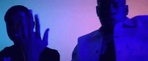 A Couple Of Men Are Standing Next To Each Other In A Dark Room With A Blue Light Behind Them . GIF