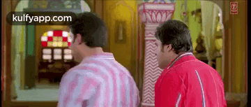 A Couple Of Men Are Standing Next To Each Other In A Room . GIF