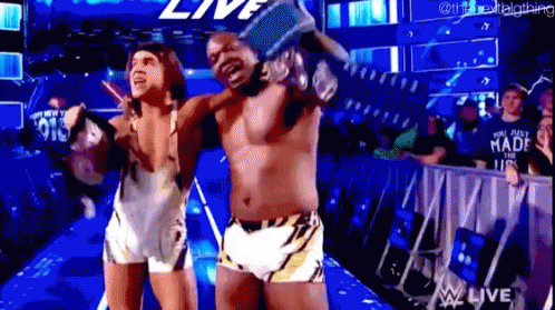 A Couple Of Men Are Standing Next To Each Other In A Wrestling Ring Holding A Trophy . GIF