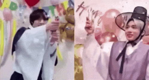 A Couple Of Men Are Standing Next To Each Other In Front Of Balloons And A Wall . GIF