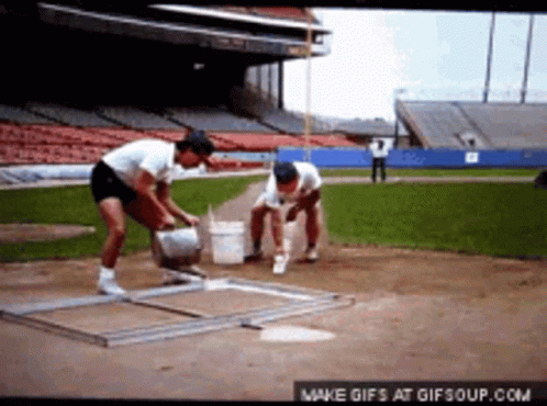 A Couple Of Men Are Working On A Baseball Field GIF