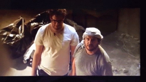 A Couple Of Men Standing Next To Each Other In A Room GIF