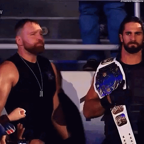 A Couple Of Men Standing Next To Each Other In A Stadium . One Of The Men Is Wearing A Championship Belt . GIF