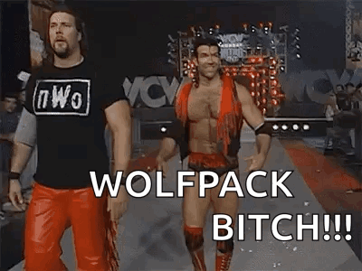 a couple of men standing next to each other on a red carpet with the words `` wolfpack bitch '' written on it .