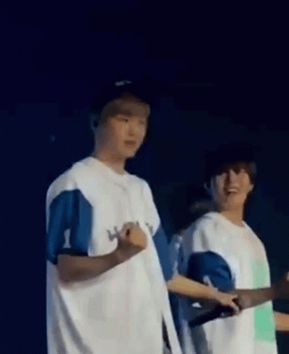 A Couple Of Men Standing Next To Each Other On A Stage . GIF