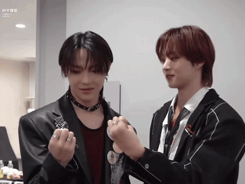 A Couple Of Men Standing Next To Each Other With The Word Hybe On The Bottom Left GIF