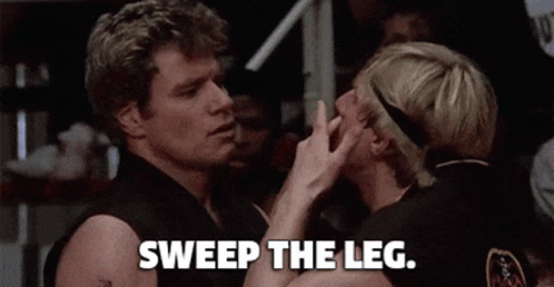 A Couple Of Men Standing Next To Each Other With The Words `` Sweep The Leg '' Written On The Bottom . GIF