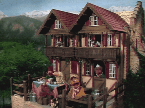 A Couple Of Muppets Are Sitting Outside Of A House GIF