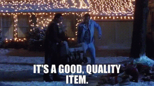 A Couple Of People Are Standing In Front Of A House With Christmas Lights On It . GIF