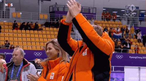 a couple of people giving each other a high five in front of a pyeongchang sign