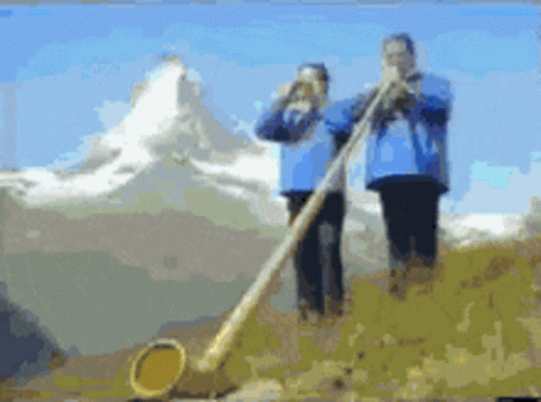 A Couple Of People Playing A Horn In Front Of A Mountain GIF