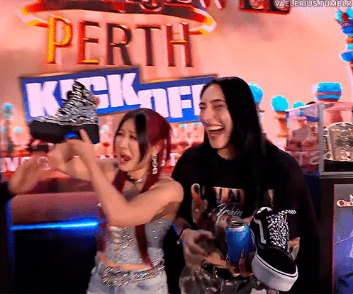 A Couple Of People Standing In Front Of A Sign That Says Perth Kick Off GIF