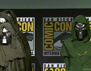A Couple Of People Standing In Front Of Comic Con Posters GIF