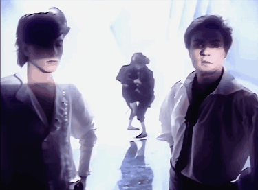 A Couple Of People Standing Next To Each Other In A White Room GIF