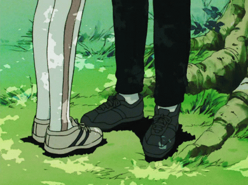 A Couple Of People Standing Next To Each Other With Their Feet In The Grass GIF