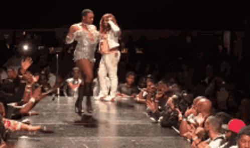 A Couple Of People Walking Down A Runway In Front Of A Crowd Of People GIF