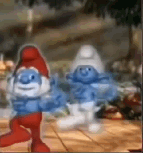 A Couple Of Smurfs Standing Next To Each Other On A Table . GIF