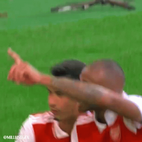 a couple of soccer players are standing on a field and one of them is pointing at the camera .
