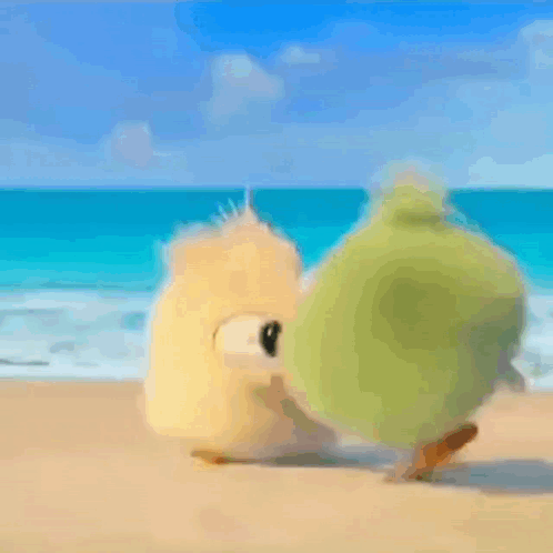A Couple Of Stuffed Animals Are Standing On A Sandy Beach Near The Ocean . GIF
