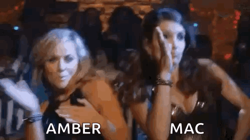 A Couple Of Women Are Standing Next To Each Other In A Dark Room . GIF