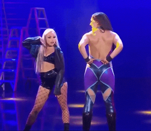 A Couple Of Women Are Standing Next To Each Other On A Stage . GIF