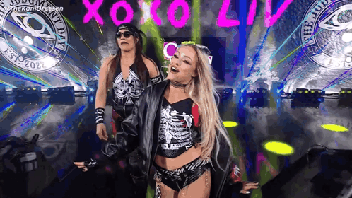 A Couple Of Women Are Standing On A Stage In Front Of A Crowd . GIF