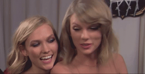A Couple Of Women Standing Next To Each Other Smiling And Laughing . GIF