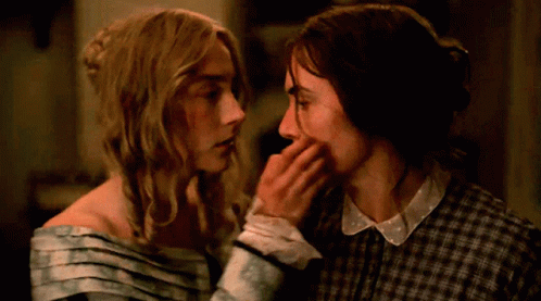 A Couple Of Women Touching Each Other 'S Faces In A Dark Room GIF