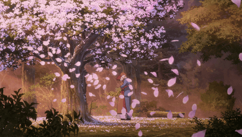 A Couple Standing Under A Tree With Petals Falling Around Them GIF