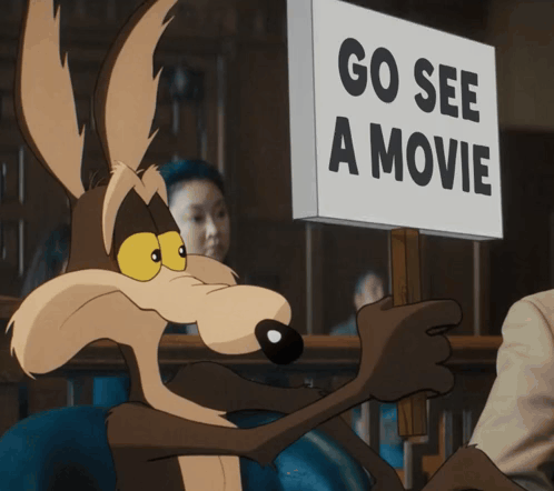a coyote is holding up a sign that says go see a movie