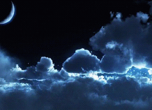 A Crescent Moon Is Visible In The Night Sky Above The Clouds GIF