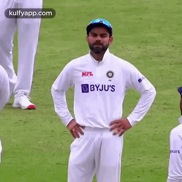 A Cricket Player Is Standing On A Field With His Hands On His Hips And Looking At The Camera . GIF