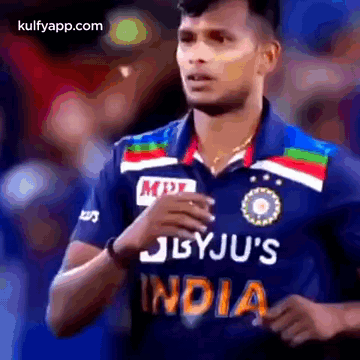 a cricket player wearing a blue jersey with the word india on it .