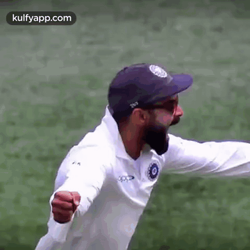 A Cricket Player Wearing A White Shirt And A Blue Hat Is Flying Through The Air . GIF