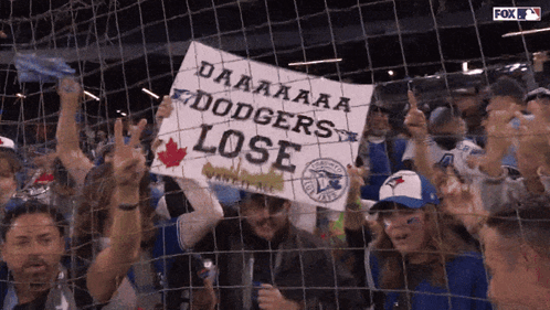 A Crowd Of Blue Jays Fans Holding A Sign That Says Dodgers Lose GIF